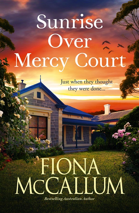 Book cover SUNRISE OVER MERCY COURT by Fiona McCallum showing at top an orange sky and below a modern traditional style bluestone house with green lawn and pale pink roses out the front.